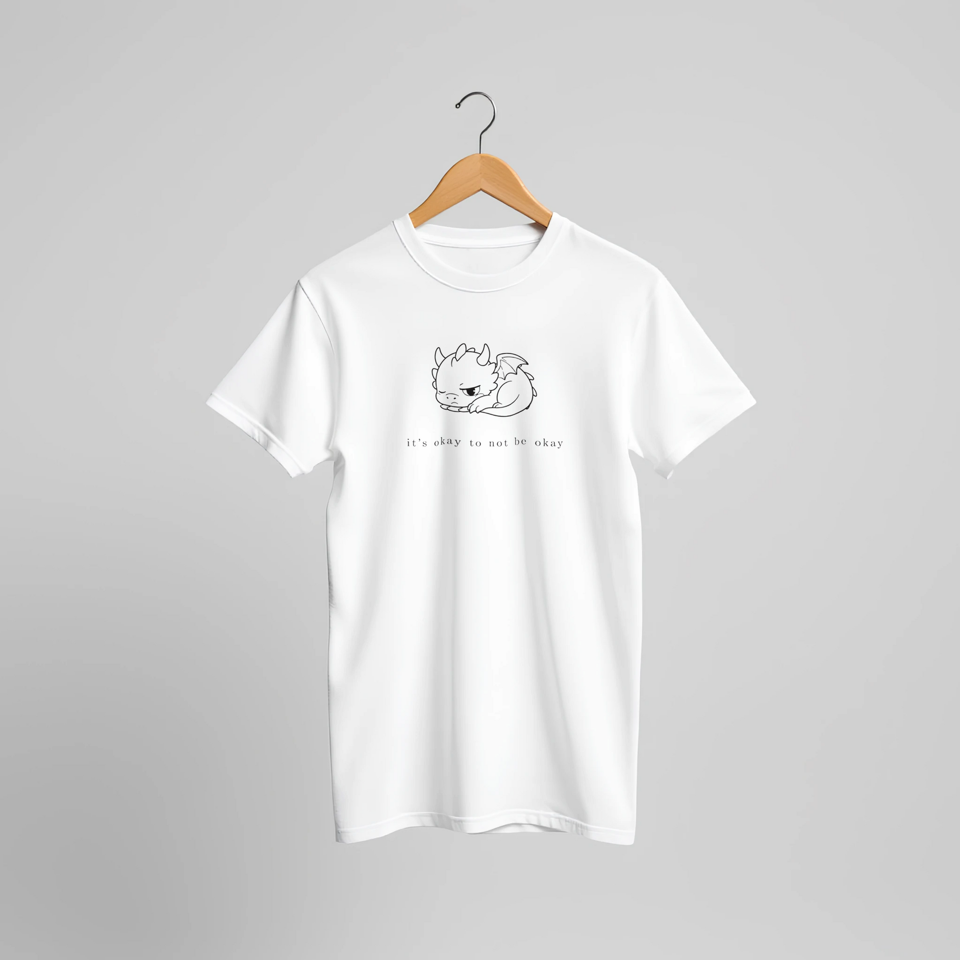 White dragon mental health t-shirt on wooden hanger against neutral background